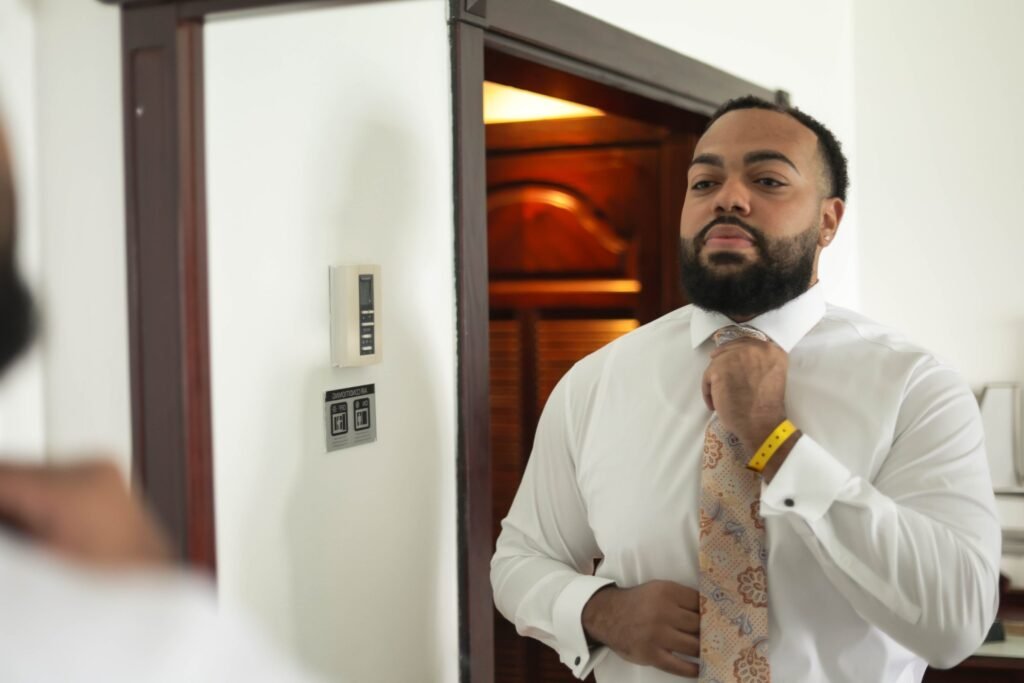 Groom tying his tie while getting ready — photographed by 121 Media Group