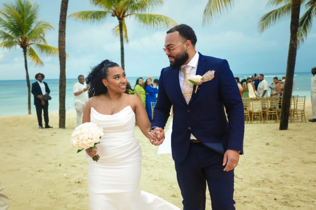 Bride and groom walking hand in hand on the beach — photographed by 121 Media Group