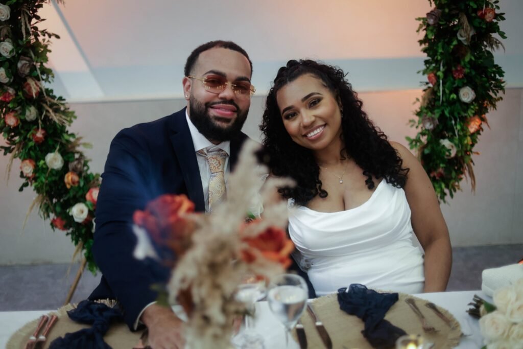 Bride and groom smiling at their sweetheart table — photographed by 121 Media Group