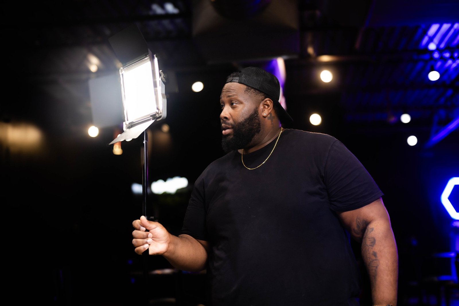 121 Media Group crew member holding an LED light and directing on set