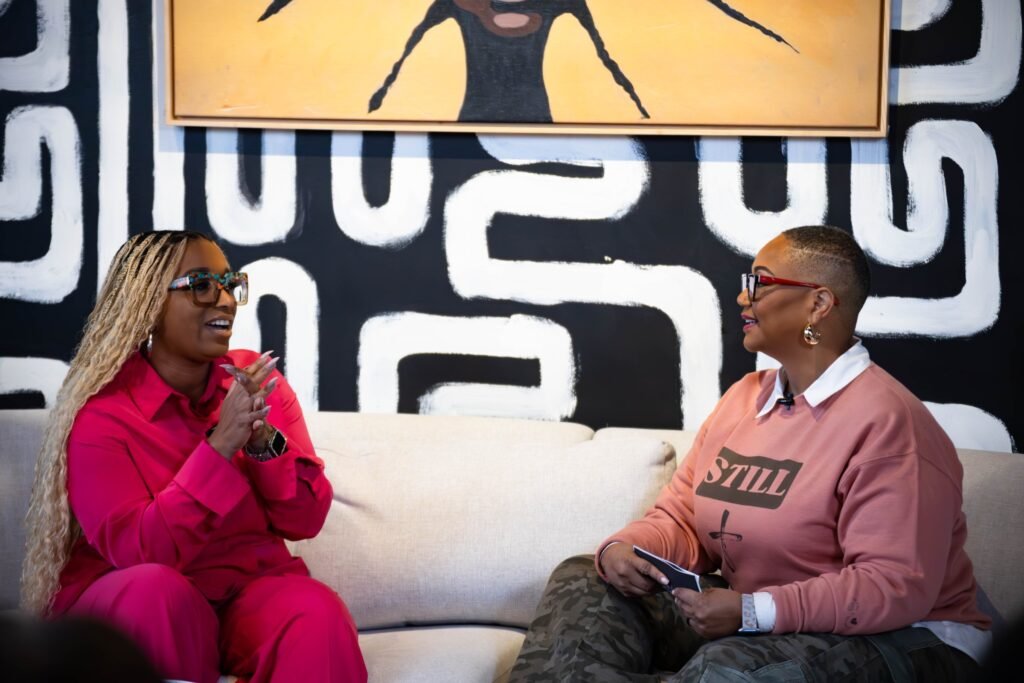 Host and guest in conversation on a white sofa during a podcast recording — photographed by 121 Media Group