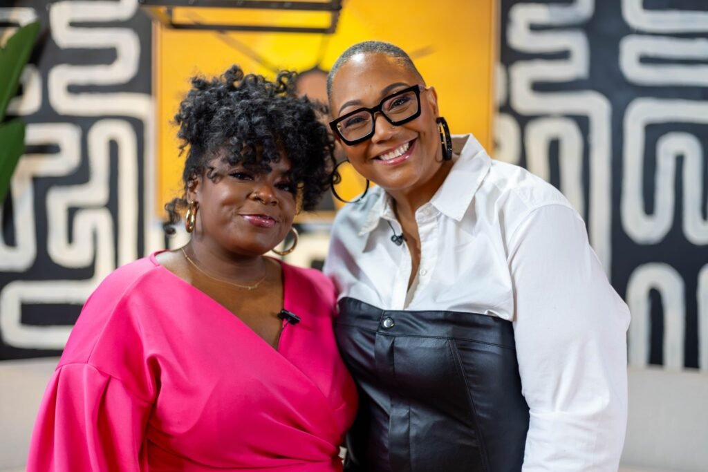 Two women embracing and smiling on the podcast set — photographed by 121 Media Group